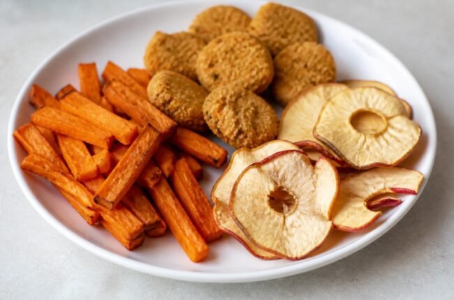 Plate of sweet potato fries, veggie nuggets and apple chips made in an air fryer