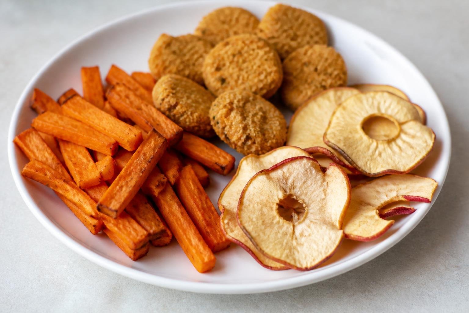 Plate of sweet potato fries, veggie nuggets and apple chips made in an air fryer