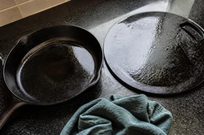 Seasoned black cast iron skillet and tawa with a cleaning cloth