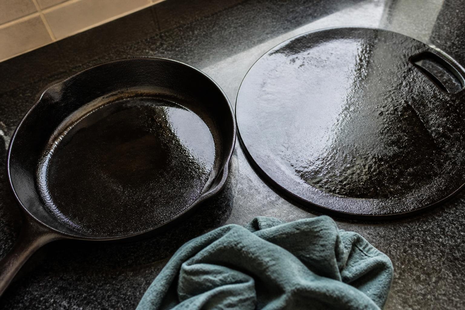 Seasoned black cast iron skillet and tawa with a cleaning cloth